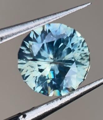 A blue Australian sapphire held in tweezers